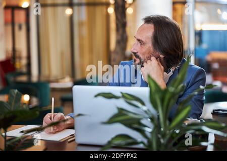 Attractive middle-aged man doing his job remotely from hotel Stock Photo