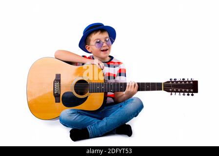 A boy kid plays guitar on a white background in the studio. Stock Photo