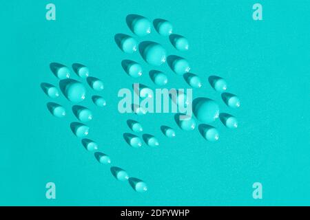 Water drops in the shape of naive flowers on blue aqua background. Watering, gardening, hydration. Fresh water, organic product and environment concep Stock Photo