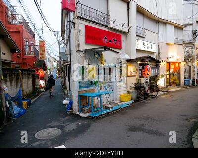 A solo man walks down an alleyway past restaurants and Izakaya in Itabashi City, Tokyo. Stock Photo