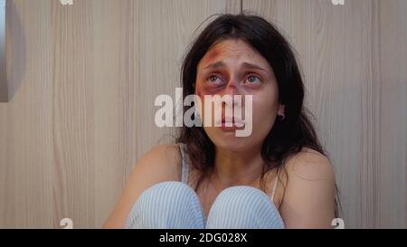 Alcoholic husband holding a bottle of wine looking at scared wife. Violent aggressive man abusing injuring terrified vulnerable, afraid, beaten and panicked woman living in terror and pressure Stock Photo