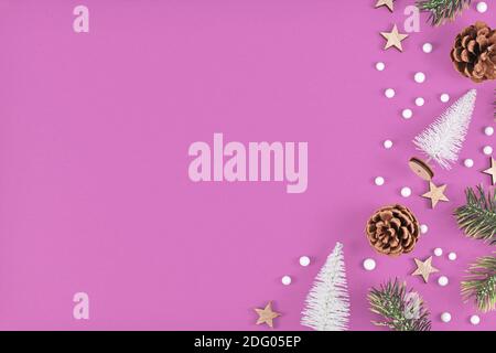 White miniature Christmas trees, snowballs, pine branches and cones and star ornaments at side of violet background with copy space Stock Photo