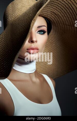 Beauty woman in a large wicker hat and light summer dress. Smokey makeup, perfect portrait of a woman Stock Photo