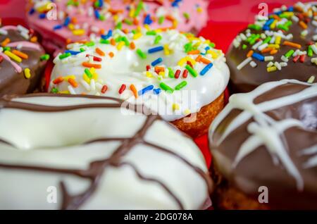 Closeup of various flavored donuts with colorful sugar strands sprinkled on them Stock Photo