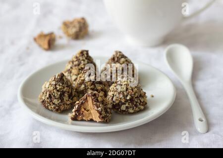 Homemade  truffles with peanut butter, chocolate glaze and waffle crumbs on a table with a cup of tea, selective focus Stock Photo