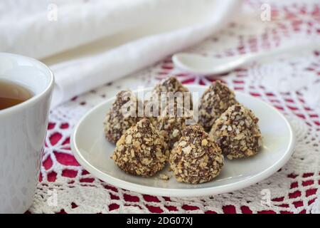 Homemade  truffles with peanut butter, chocolate glaze and waffle crumbs on a table with a cup of tea, selective focus Stock Photo