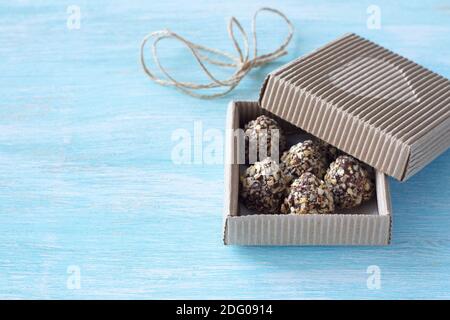 Candies with peanut butter, chocolate glaze and waffle crumbs in a festive craft box on a blue background, selective focus, free space. Delicious home Stock Photo