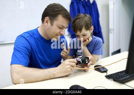 Father with his son programming robot at table in workshop Stock Photo
