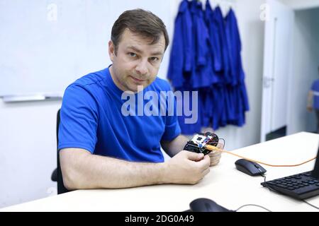 Man programming robot at table in workshop Stock Photo