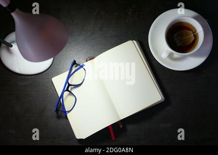 high angle view of open notepad and table lamp on wooden background  Stock Photo
