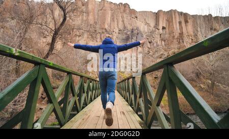 Happy tourist runs on a bridge over a river in the Ihlara Valley in Cappadocia, Turkey. Stock Photo