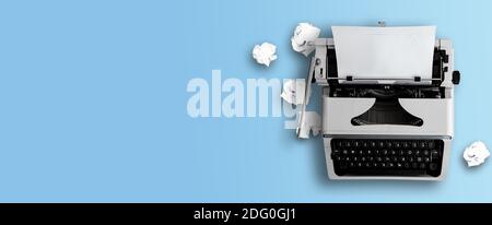 top view of old typewriter and crumpled paper balls on blue desk background, writing or blogging concept Stock Photo