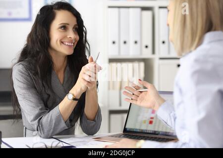 Business women smiling and talking at table in office Stock Photo