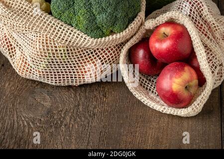 Zero-waste concept - fresh red apples and broccoli in ecological reusable mesh bags made of organic cotton, with copy space Stock Photo