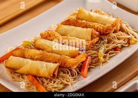 Close up of fried Chinese spring rolls and crispy shrimps served with pasta Stock Photo