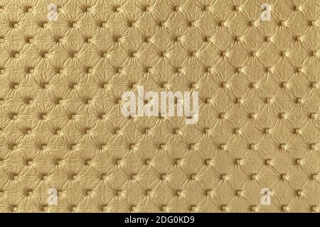 Texture of golden leather background with capitone pattern, macro. Yellow textile of retro Chesterfield style. Vintage fabric backdrop. Stock Photo