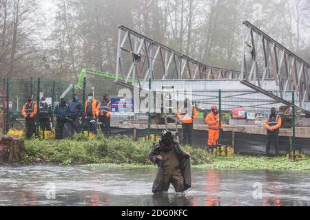 Denham, UK. 7th December, 2020. An anti-HS2 activist crosses the river Colne where contractors working on behalf of HS2 Ltd are trying to construct a bridge for works in connection with the HS2 high-speed rail link. Anti-HS2 activists continue to resist the controversial £106bn rail project from a series of protest camps based along its initial route between London and Birmingham. Credit: Mark Kerrison/Alamy Live News Stock Photo