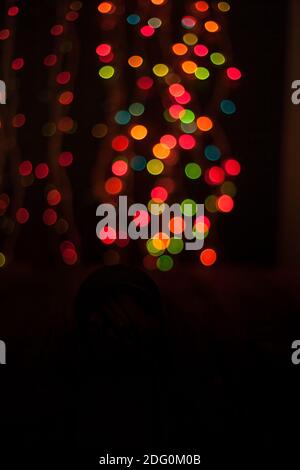 Multicolored bokeh on a black background. Multicolored lights from the Christmas garland. Good New Year spirit. Blurred focus Stock Photo