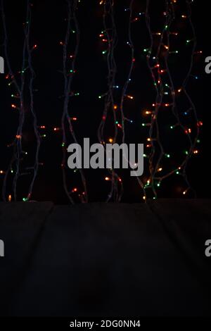 Multicolored bokeh on a black background. Multicolored lights from the Christmas garland. Good New Year spirit. Blurred focus Stock Photo