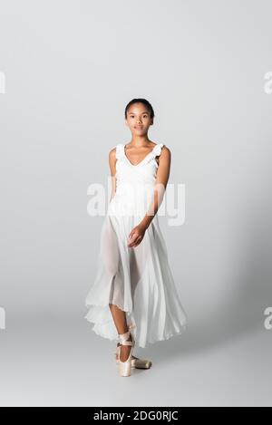 graceful african american ballerina in dress dancing on white background Stock Photo