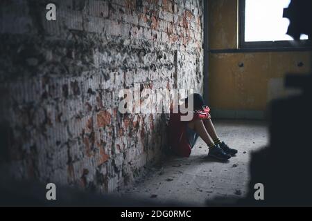 Sad and disappointed teenagers boy sitting indoors in abandoned building. Stock Photo