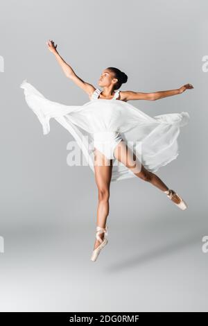 graceful african american ballerina in dress dancing on white background Stock Photo