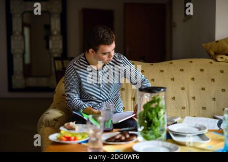 Down syndrome adult man sitting indoors at home, resting on sofa. Stock Photo