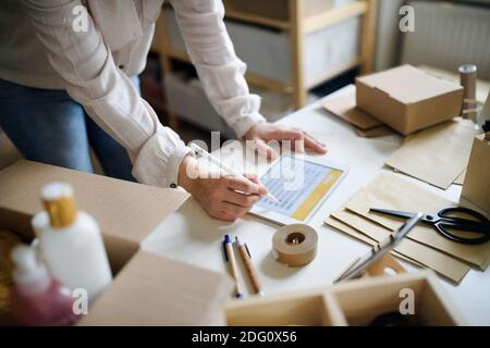 Unrecognizable woman dropshipper working at home, using tablet. Coronavirus concept. Stock Photo