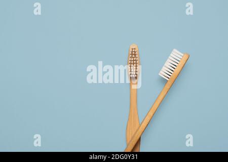 Two natural wooden bamboo toothbrushes flay lay on a blue background with copy space and room for text with a right side composition Stock Photo