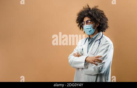 Sad mature man doctor with face mask in standing in studio, coronavirus concept. Stock Photo