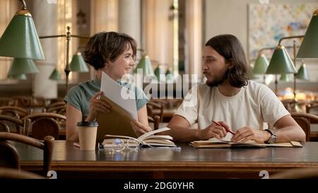 Attractive smiling college students happily opening exam results. Young students studying together in university Stock Photo