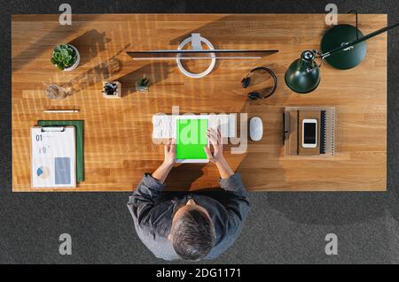Top view of businessman working on computer at desk with keyable screen in home office. Stock Photo