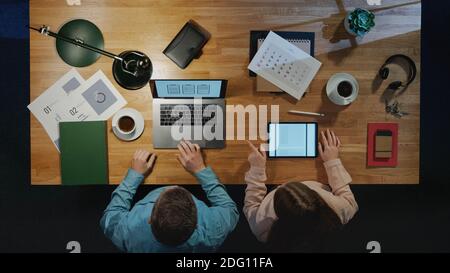 Top view of business people working on computer at desk with paperwork in home office. Stock Photo