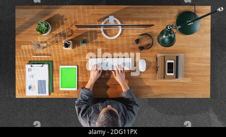 Top view of businessman working on computer at desk with keyable screen in home office. Stock Photo