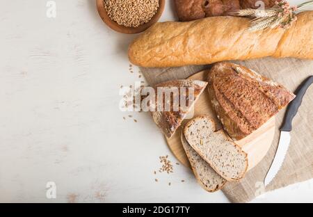 Sliced bread with different kinds of fresh baked bread on a white wooden background. top view, flat lay, copy space. Stock Photo