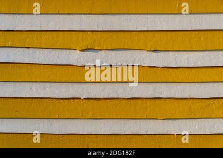 wooden planks painted in yellow and white horizontal stripes. Background. Stock Photo