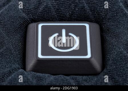 Macro shot of a plastic button with a white power symbol, sewn into modern clothing. Stock Photo