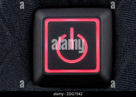 Macro shot of a plastic button with a red power symbol, sewn into modern clothing, top view. Stock Photo