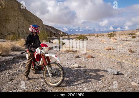 Death Valley, California / USA : 24 Dec 2019: A male tourist rides a dirtbike on the back roads of Death Valley on a winter day. Stock Photo