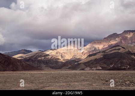A view of Artist's Pallete in Death Valley National Park on a sunny day with dramatic clouds. A view of Artist's Pallete in Death Valley National Park on a sunny day with dramatic clouds.