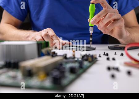 electronics repair service. technician working in office. repairing phone Stock Photo