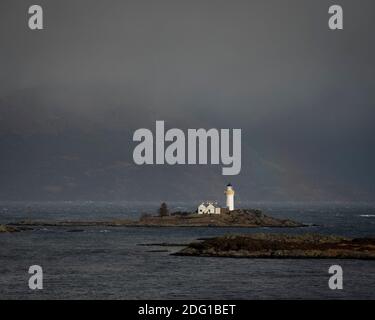 The lighthouse and cottage on Eilean Sionnach, on a showery day with a hint of a rainbow. Ornsay, Isle of Skye, Scotland Stock Photo