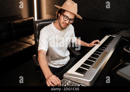 Young musician composing new song on midi piano in sound recording studio. Attractive guy playing on electric piano in studio Stock Photo