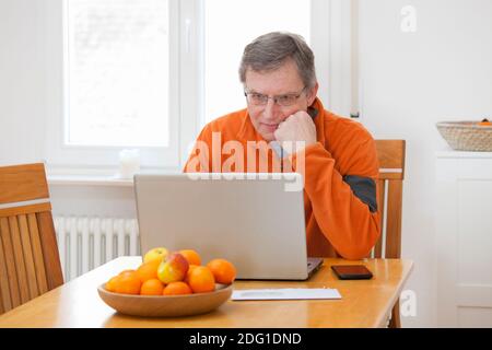 Mature man working from home with laptop and smart phone - focus on the face Stock Photo