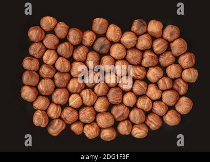 Hazelnuts heap on a black  Background. Top view. Flat lay. Hazelnuts pile Stock Photo
