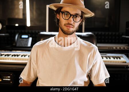 Young stylish sound producer confidently looking in camera working in recording studio Stock Photo