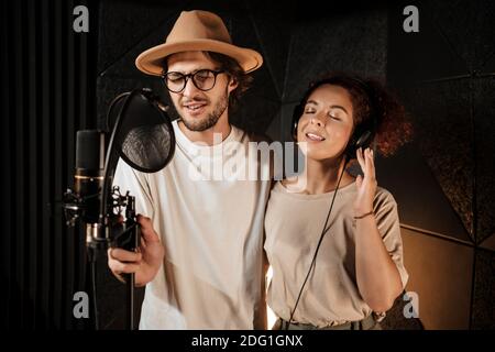 Portrait of young attractive man and woman sensually singing together recording song in studio Stock Photo