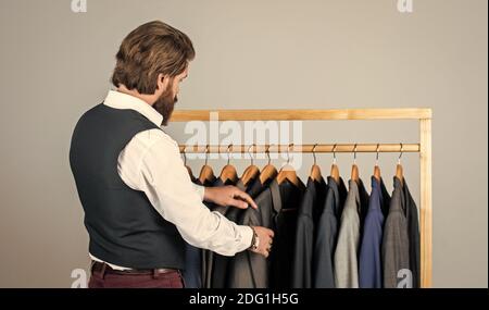 Man picking suit from personal wardrobe, tailored clothes concept. Stock Photo