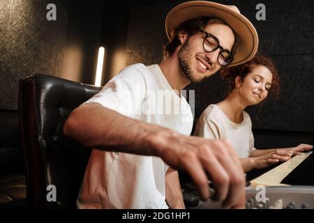 Young stylish people creating music in modern recording studio. Attractive musicians happily working in studio Stock Photo