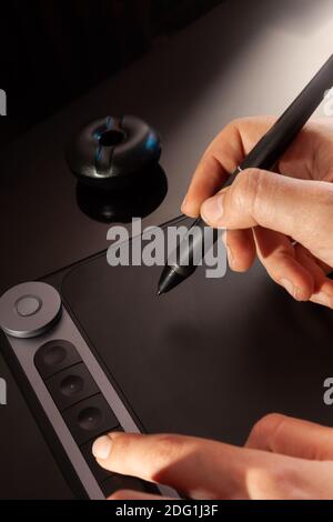 Graphic designer working with graphics tablet. Dark background Stock Photo